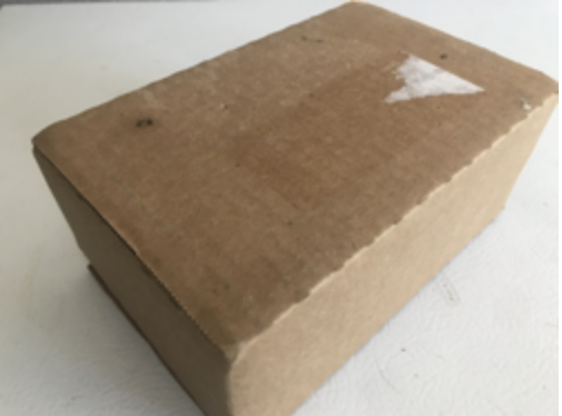 Photo of a shipping box, taken from an angle where it shows the bottom of the box and the two sides not shown in the previous picture